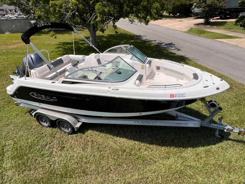Slide: The Image of 2021 Robalo R227 Dual Console boat on trailer, parked on grass. - 0