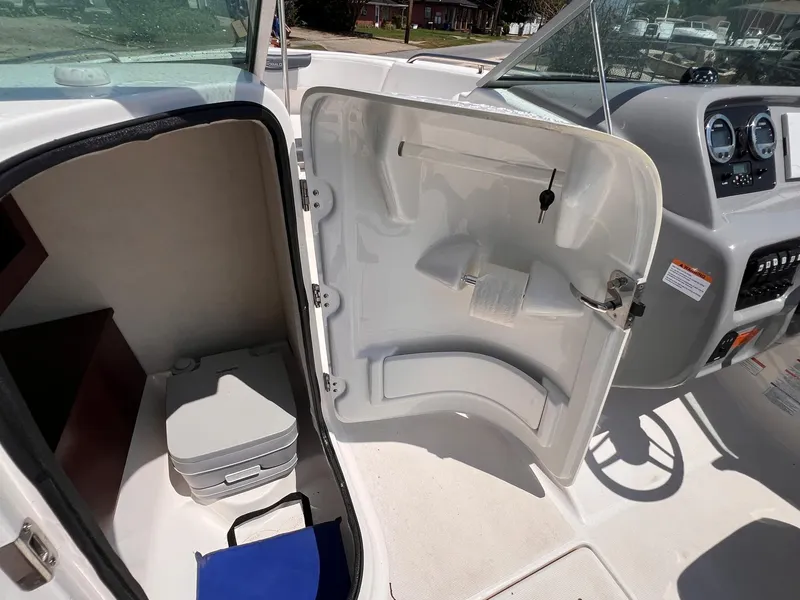 Slide: The Image of 2021 Robalo R227 Dual Console boat interior with storage compartment and portable toilet. - 14