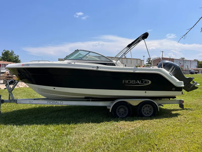 Slide: The Image of 2021 Robalo R227 Dual Console boat on trailer, parked on grass. - 2