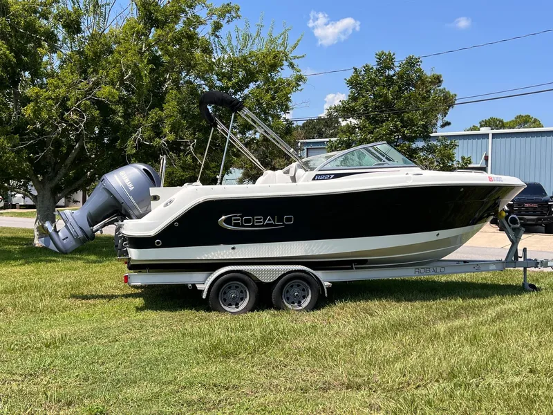Slide: The Image of 2021 Robalo R227 Dual Console boat on trailer, parked on grass. - 3