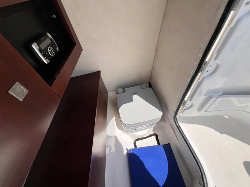 Slide: The Image of 2021 Robalo R227 Dual Console interior with portable toilet and storage. - 9