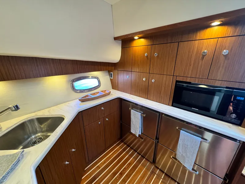 Slide: The Image of Luxurious 2019 Tiara Yachts 4300 Open kitchen with wood cabinetry and modern appliances. - 25