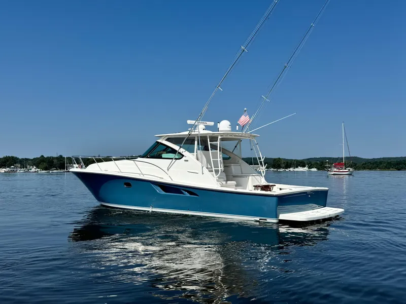 Slide: The Image of 2019 Tiara Yachts 4300 Open on calm water, blue hull, fishing rods visible. - 7