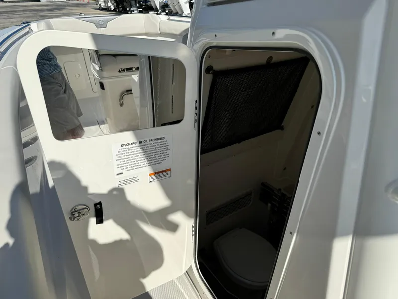 Slide: The Image of 2025 Sailfish 272 CC boat interior with open door revealing compact bathroom. - 27