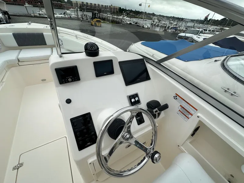 Slide: The Image of 2025 Cobia 240 Center Console boat dashboard with steering wheel and navigation screens. - 17