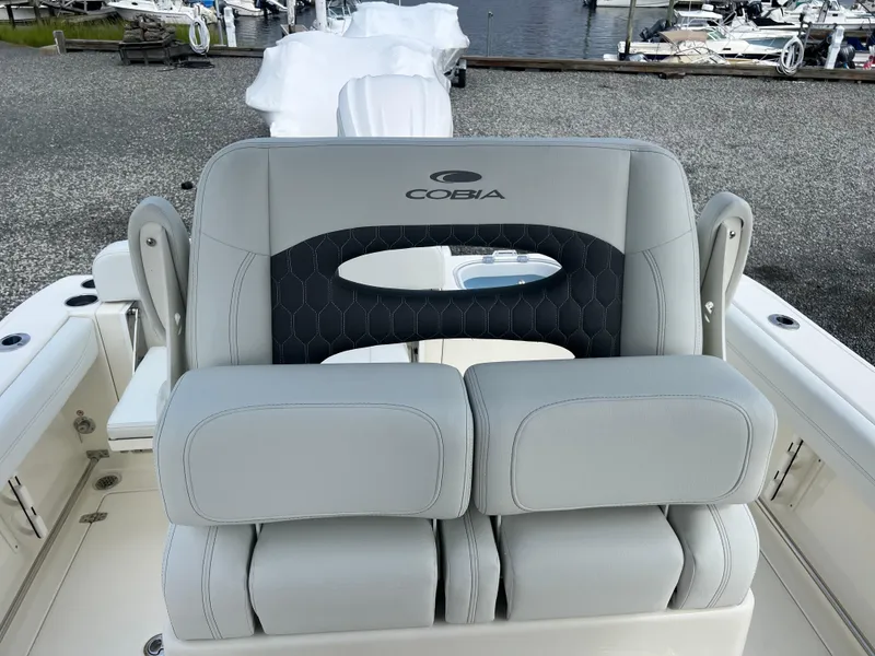 Slide: The Image of 2025 Cobia 240 Center Console boat seat with logo, docked at marina. - 23