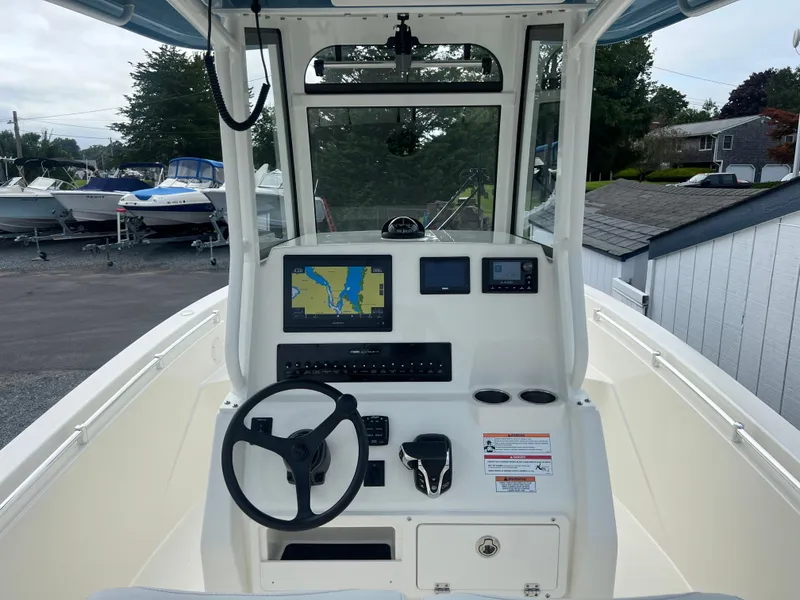 Slide: The Image of 2025 Cobia 240 Center Console boat dashboard with navigation screens and steering wheel. - 24