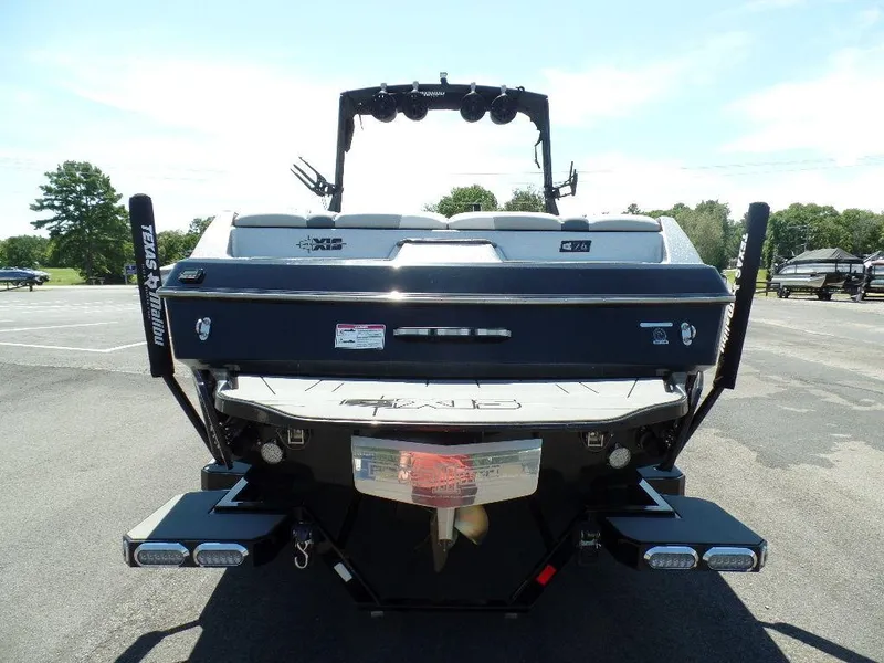 Slide: The Image of 2019 Axis A24 boat rear view in parking lot, showcasing wakeboard tower and swim platform. - 5