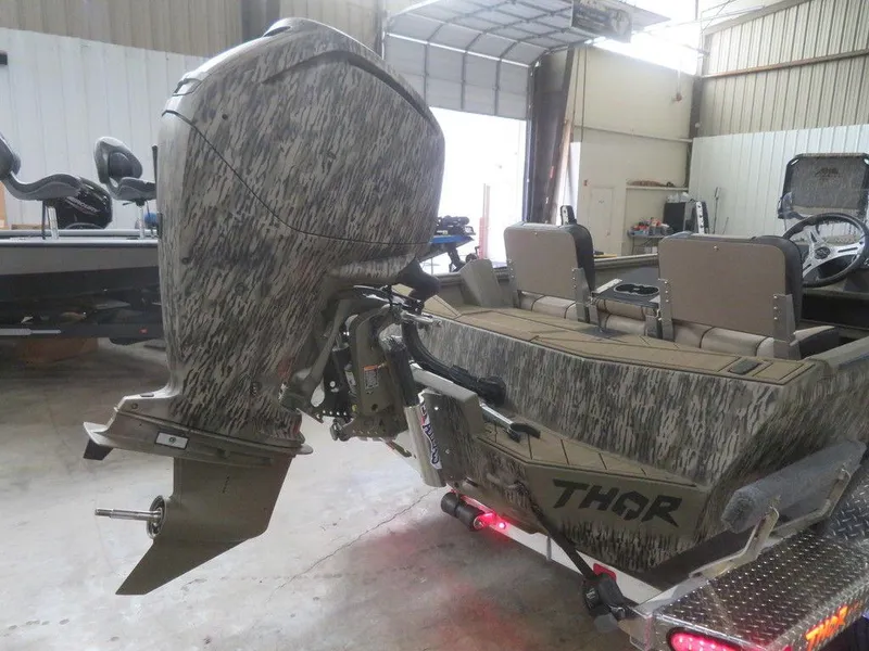Slide: The Image of 2025 Thor Lake Hammer 1860 Side Console boat with camo design in a garage. - 10