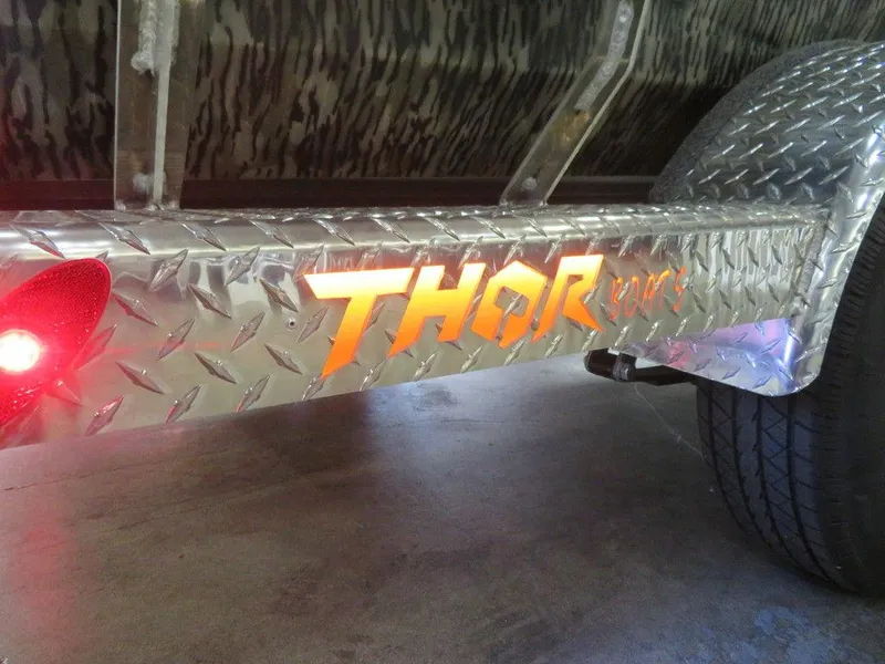 Slide: The Image of Trailer with illuminated "Thor" logo, diamond plate design, 2025 Thor LAKE HAMMER 1860 SIDE CONSOLE. - 11