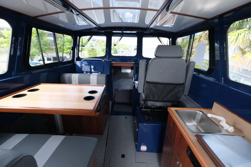 Slide: The Image of 2024 Hewescraft 250 Pacific Explorer interior with seating, table, and kitchenette. - 11