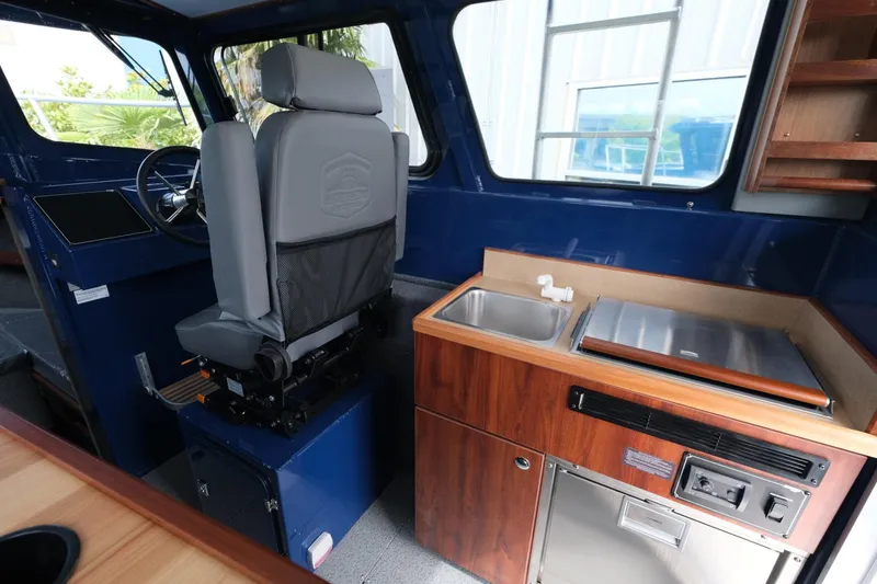 Slide: The Image of Interior of 2024 Hewescraft 250 Pacific Explorer with helm, sink, and kitchenette. - 13