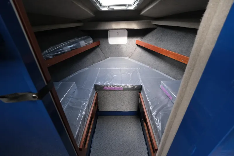 Slide: The Image of 2024 Hewescraft 250 Pacific Explorer cabin interior with cozy sleeping area and storage shelves. - 16