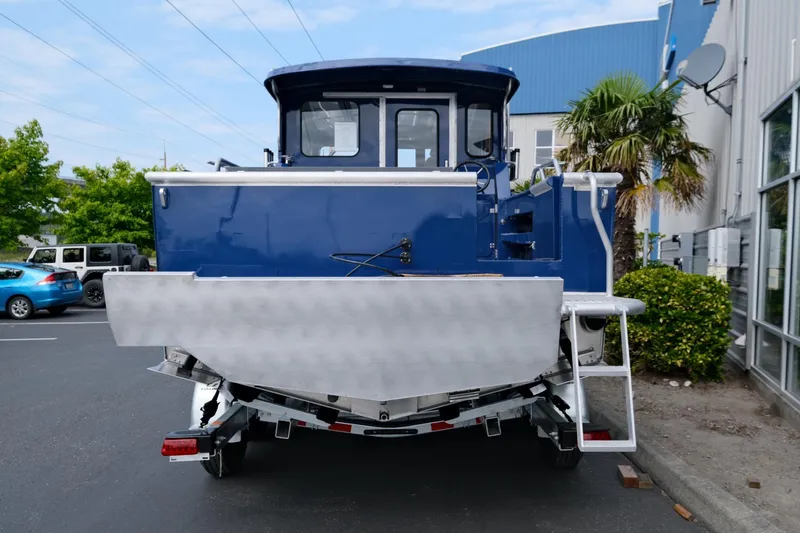 Slide: The Image of 2024 Hewescraft 250 Pacific Explorer boat, blue exterior, parked on a trailer in a lot. - 5