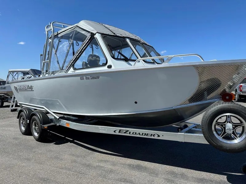 The Image of 2024 Hewescraft 210 Sea Runner boat on EZ Loader trailer under clear blue sky. - 0