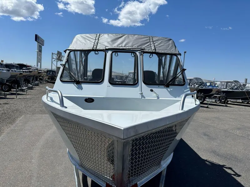 Slide: The Image of 2024 Hewescraft 210 Sea Runner boat with canopy, parked outdoors under blue sky. - 2