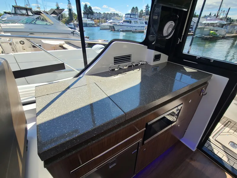 Slide: The Image of 2021 Four Winns Vista 355 Coupe OB interior with sleek kitchen countertop and marina view. - 16