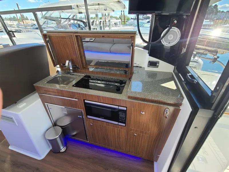 Slide: The Image of 2021 Four Winns Vista 355 Coupe OB kitchen with modern appliances and sleek wood cabinetry. - 17