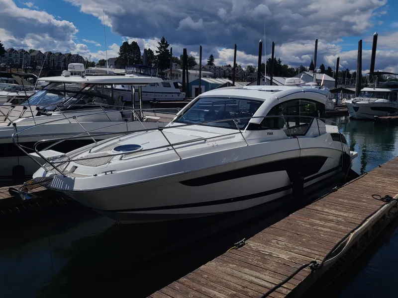 Slide: The Image of 2021 Four Winns Vista 355 Coupe OB docked at a marina under cloudy skies. - 2