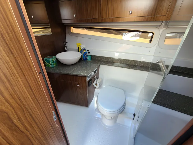 Slide: The Image of 2021 Four Winns Vista 355 Coupe OB bathroom with modern fixtures and wooden cabinetry. - 21