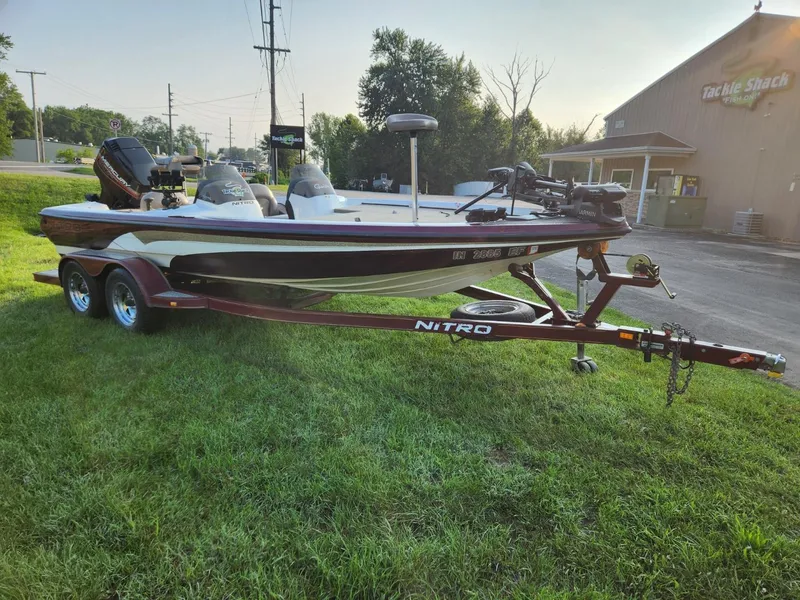 Slide: The Image of 2001 Nitro 896 DC boat on trailer, parked on grass near a tackle shop. - 6