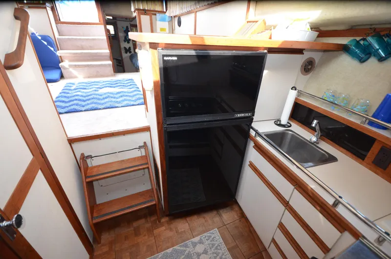 Slide: The Image of 1988 Carver 3207 yacht kitchen with fridge, sink, and wooden cabinetry. - 13