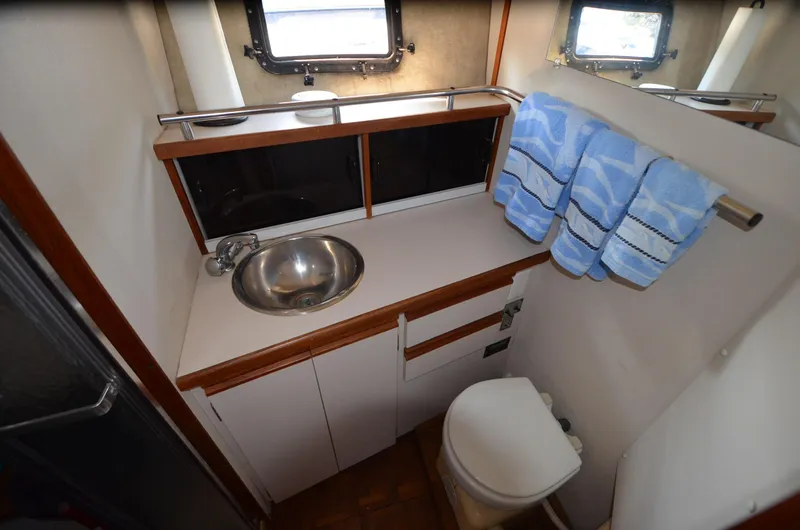 Slide: The Image of 1988 Carver 3207 yacht bathroom with sink, toilet, and storage cabinets. - 14