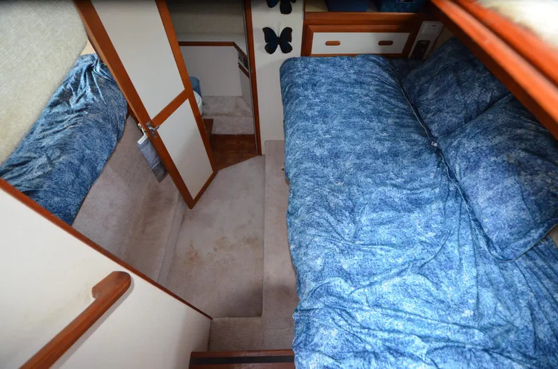 Slide: The Image of Interior of 1988 Carver 3207 boat with blue bedding and wooden accents. - 17