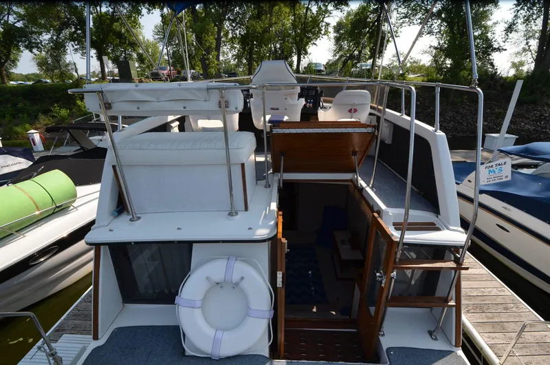 Slide: The Image of 1988 Carver 3207 boat with upper deck, docked, surrounded by trees and other boats. - 25