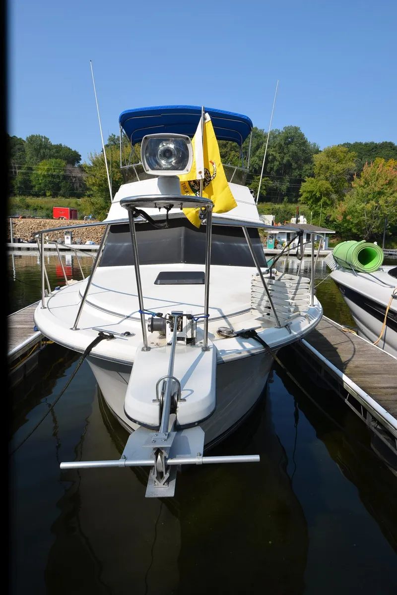 Slide: The Image of 1988 Carver 3207 boat docked, featuring a blue canopy and yellow flag. - 26