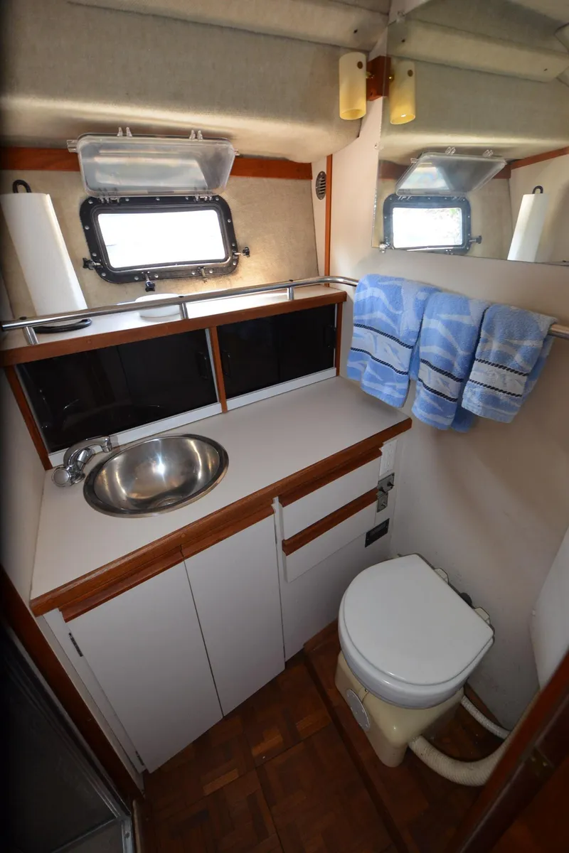 Slide: The Image of 1988 Carver 3207 yacht bathroom with sink, toilet, and porthole window. - 27
