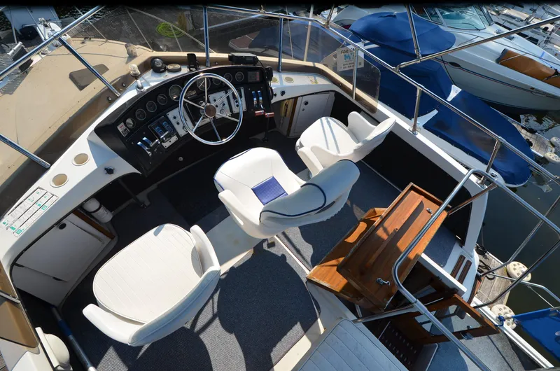 Slide: The Image of 1988 Carver 3207 boat cockpit with steering wheel, control panel, and white seating. - 5