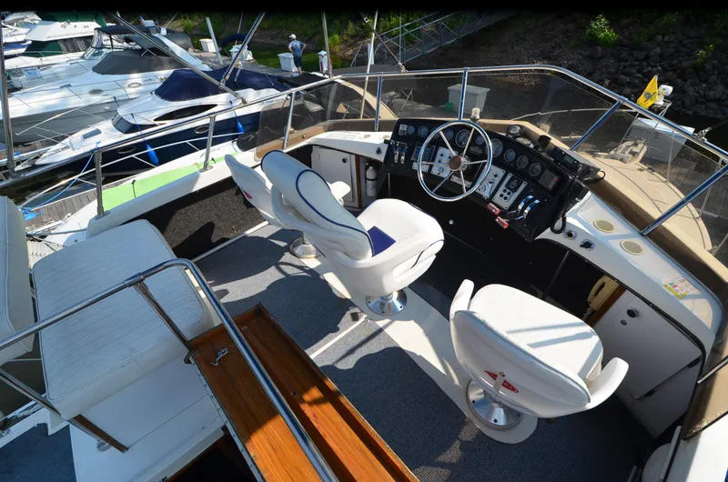 Slide: The Image of 1988 Carver 3207 boat cockpit with white seats and control panel, docked at marina. - 6