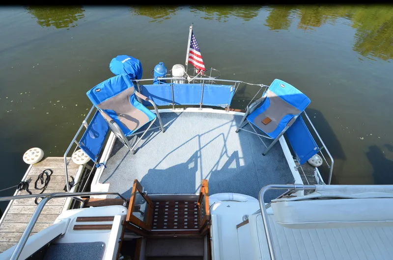 Slide: The Image of 1988 Carver 3207 boat deck with chairs and American flag on calm water. - 7