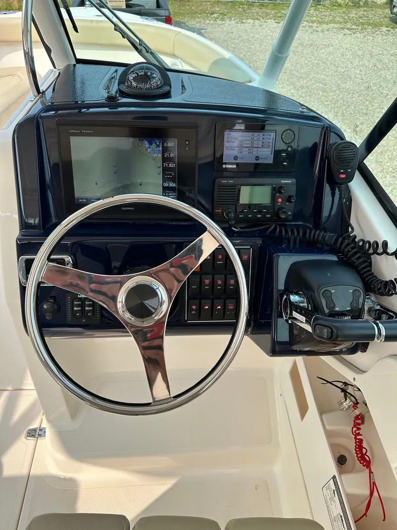 Slide: The Image of 2016 Pursuit DC 265 Dual Console boat dashboard with steering wheel and navigation controls. - 10