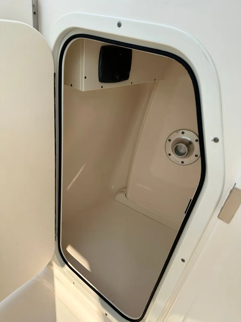 Slide: The Image of Open storage compartment on 2016 Pursuit DC 265 Dual Console boat. - 14