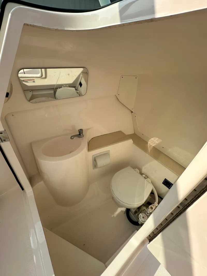 Slide: The Image of 2016 Pursuit DC 265 Dual Console boat interior with compact bathroom and sink. - 16