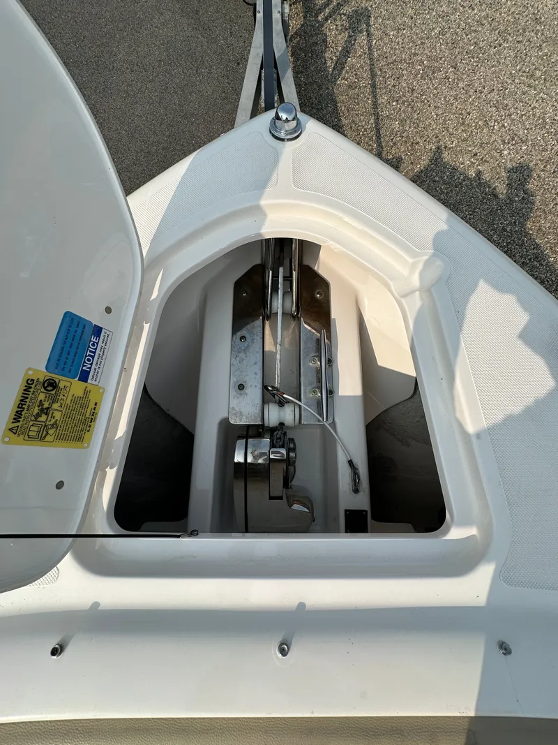 Slide: The Image of 2016 Pursuit DC 265 Dual Console anchor compartment, open lid, showing anchor mechanism. - 17