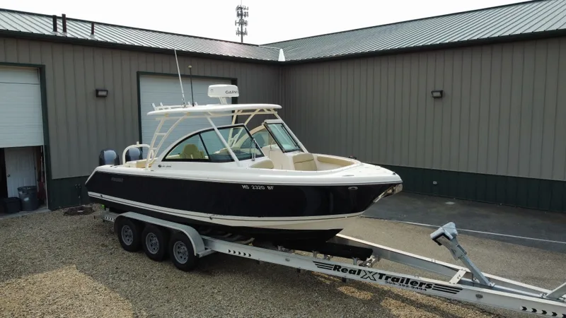 Slide: The Image of 2016 Pursuit DC 265 Dual Console boat on trailer outside a warehouse. - 3