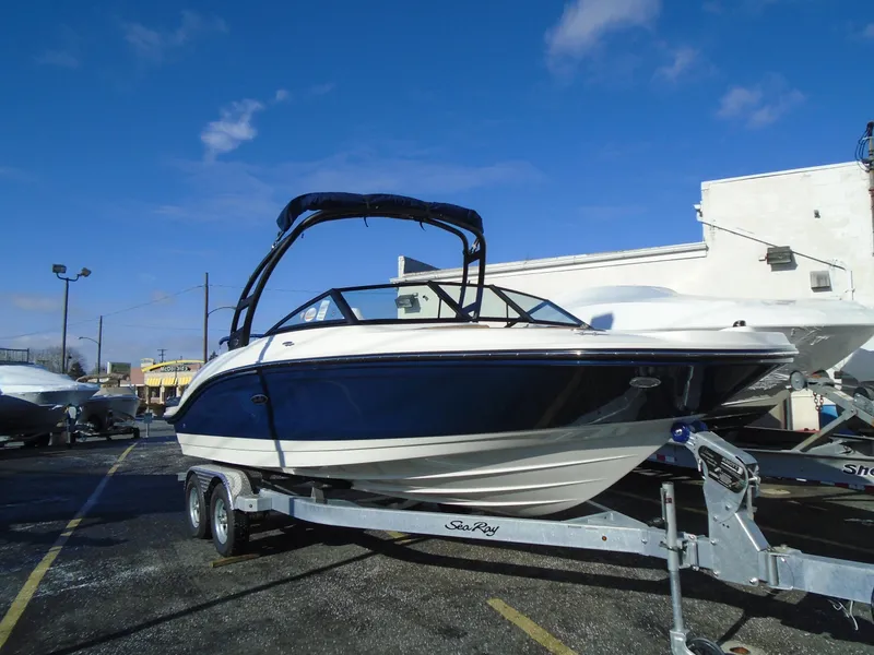 Slide: The Image of 2023 Sea Ray SPX 210 boat on trailer under clear blue sky. - 11