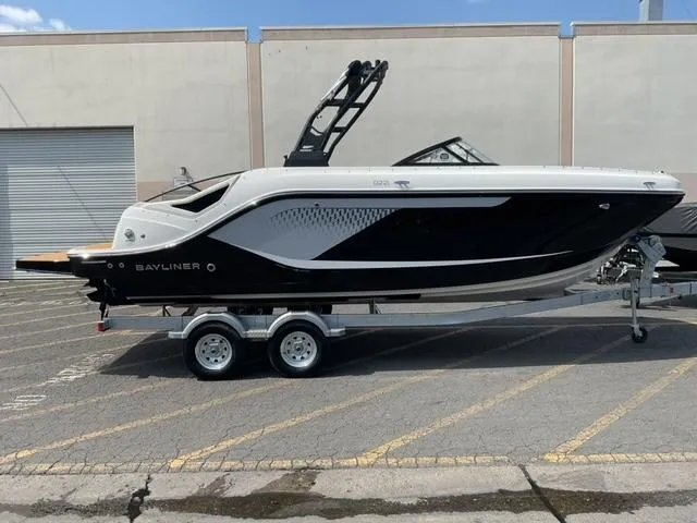 The Image of 2025 Bayliner D22I boat on trailer, sleek black and white design, parked outdoors. - 0
