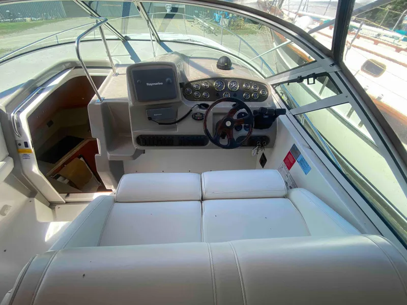 Slide: The Image of 2004 Cruisers Yachts 340 Express cockpit with white seating and helm controls. - 12
