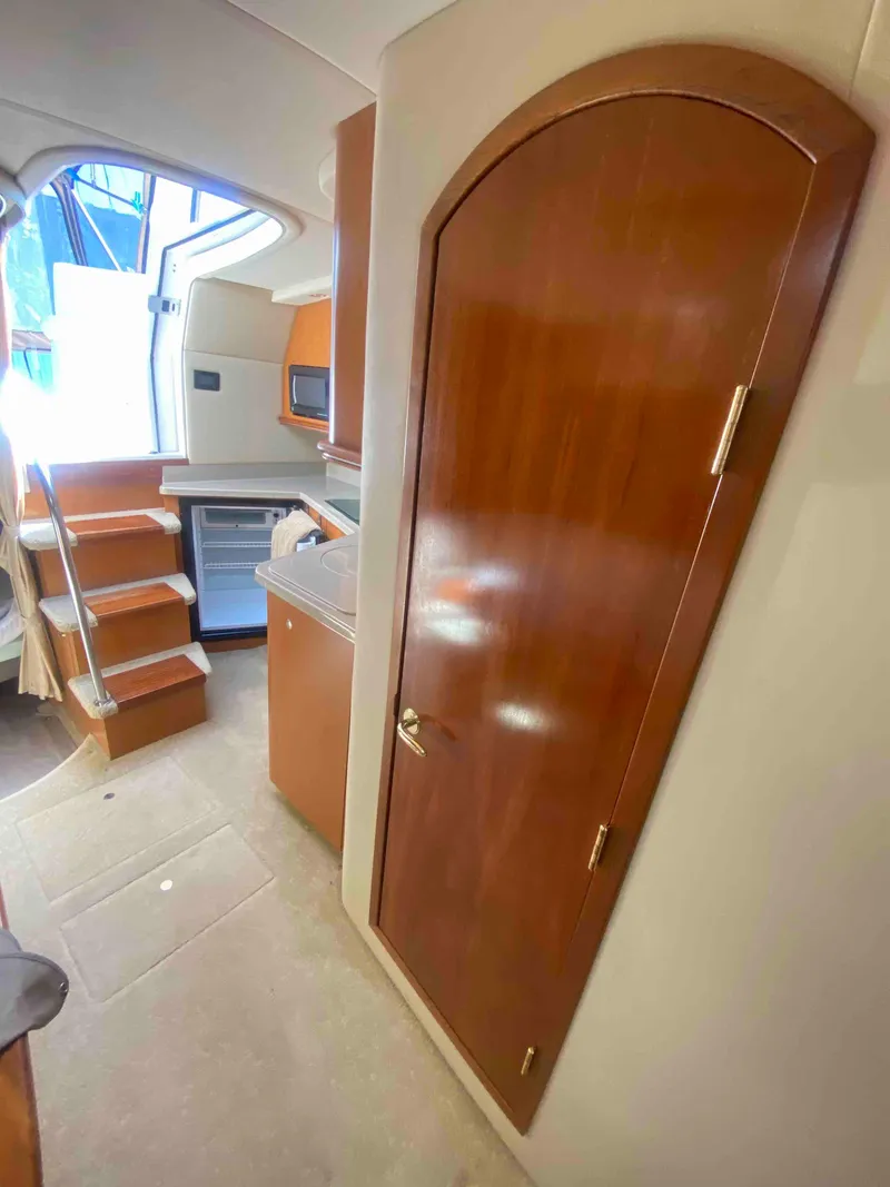 Slide: The Image of 2004 Cruisers Yachts 340 Express interior closet with wooden door and hanging rod. - 36