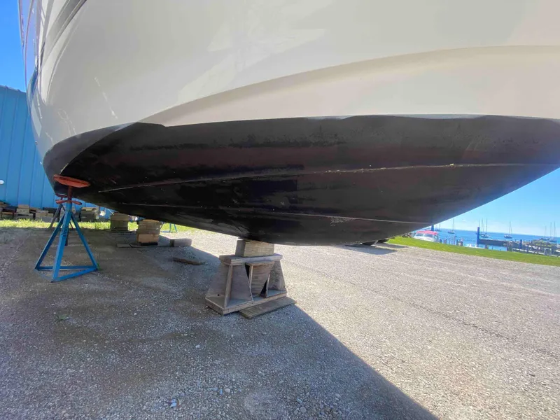 Slide: The Image of 2004 Cruisers Yachts 340 Express boat on land under bright blue sky. - 4