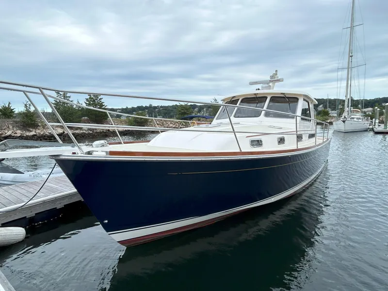 Slide: The Image of 2006 Sabre 38 Express HDTP MY yacht with striped seating and wooden table on deck. - 2