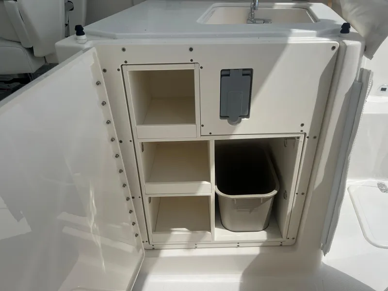 Slide: The Image of 2024 Pursuit DC 306 Dual Console boat storage compartments with sink and trash bin. - 15