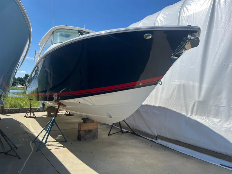 Slide: The Image of 2024 Pursuit DC 306 Dual Console boat on stands, outdoors, under clear blue sky. - 2