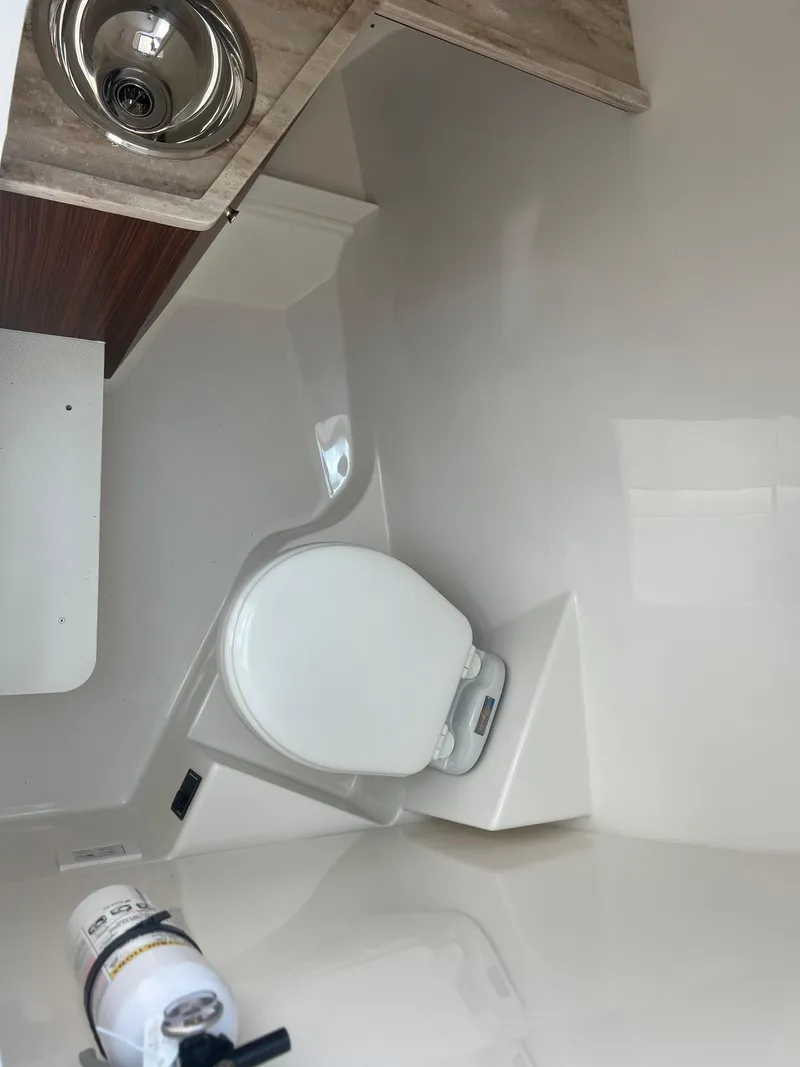 Slide: The Image of 2024 Pursuit DC 306 Dual Console boat interior with toilet and sink. - 25