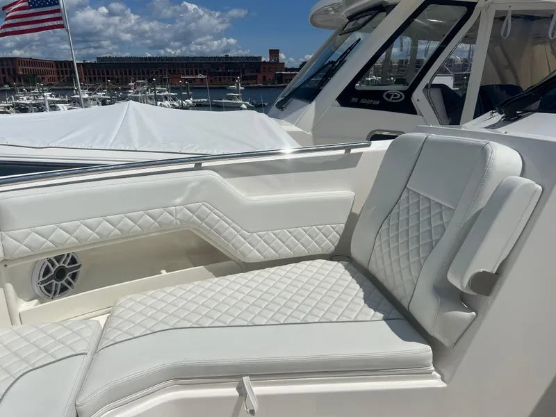Slide: The Image of 2024 Pursuit DC 306 Dual Console boat with luxurious white seating and marina backdrop. - 27