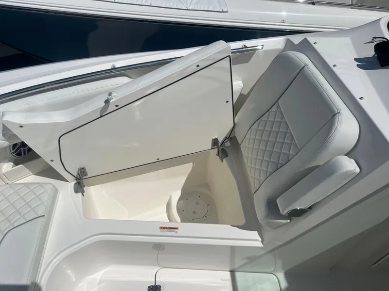 Slide: The Image of 2024 Pursuit DC 306 Dual Console boat with open storage compartment and cushioned seating. - 28